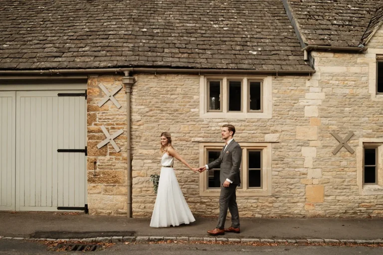 Bride & groom walking through Cotswolds village